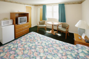 bedroom with queen bed, small fridge, microwave and tv