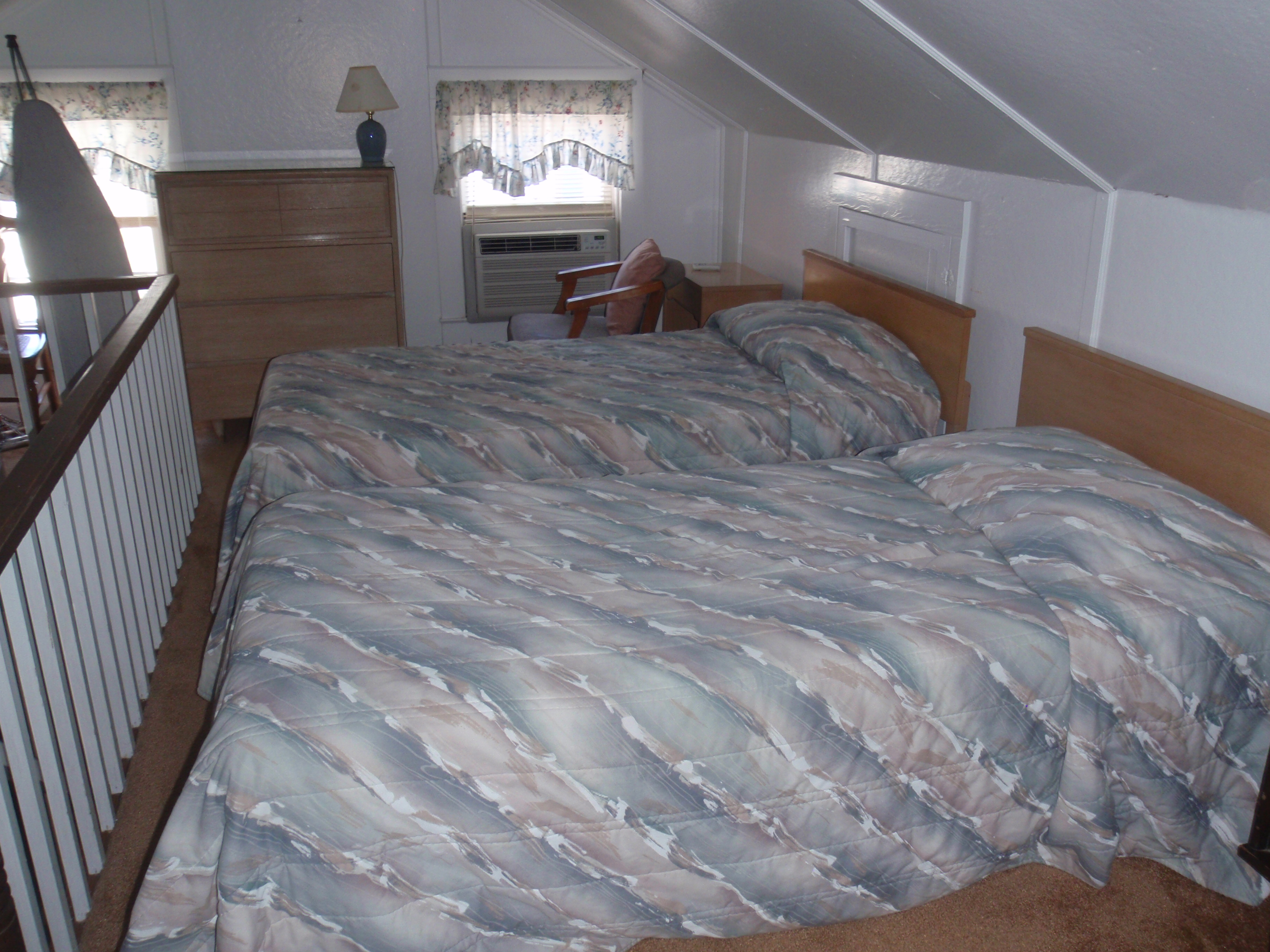loft bedroom with 2 single beds, dresser and chair