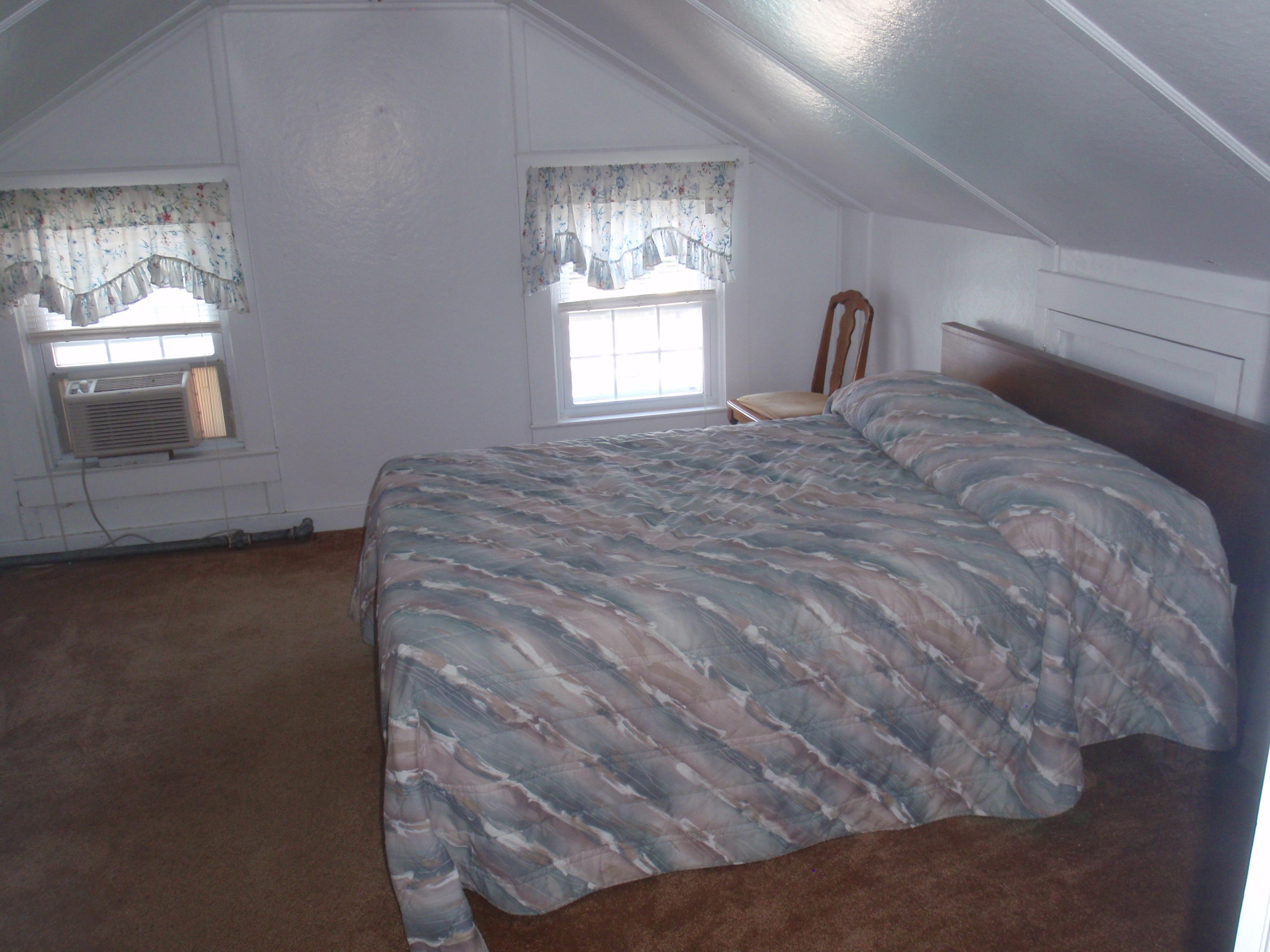 full size bed in bedroom with windows and ac unit