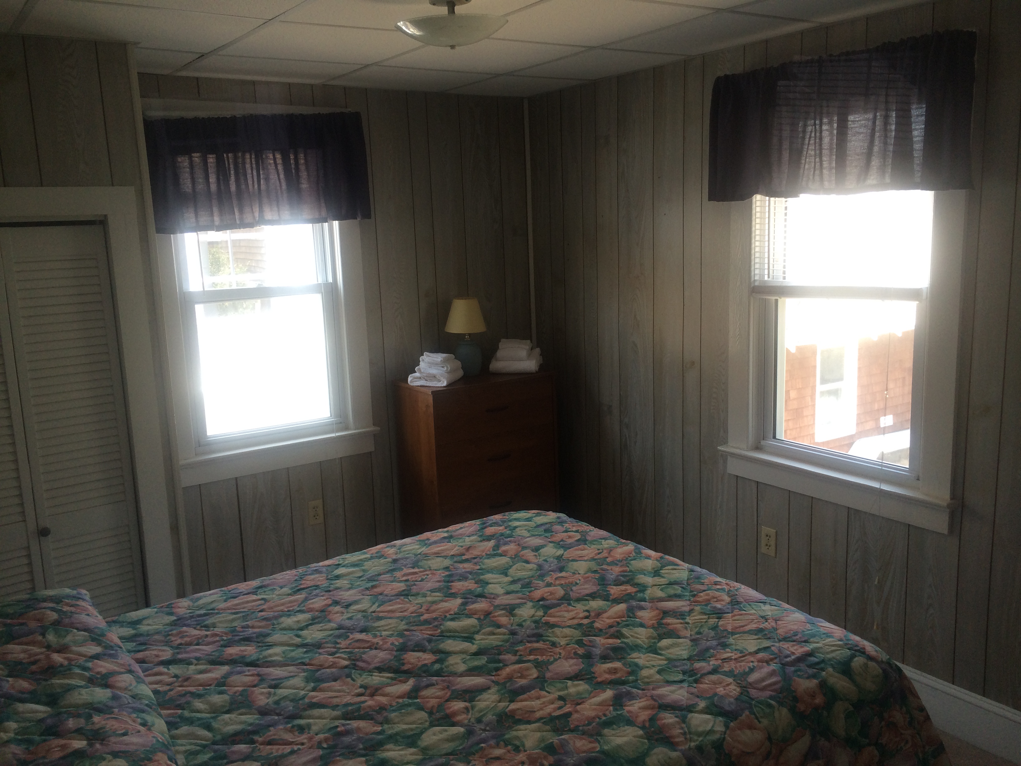 queen bed in bedroom with dresser, closet and windows