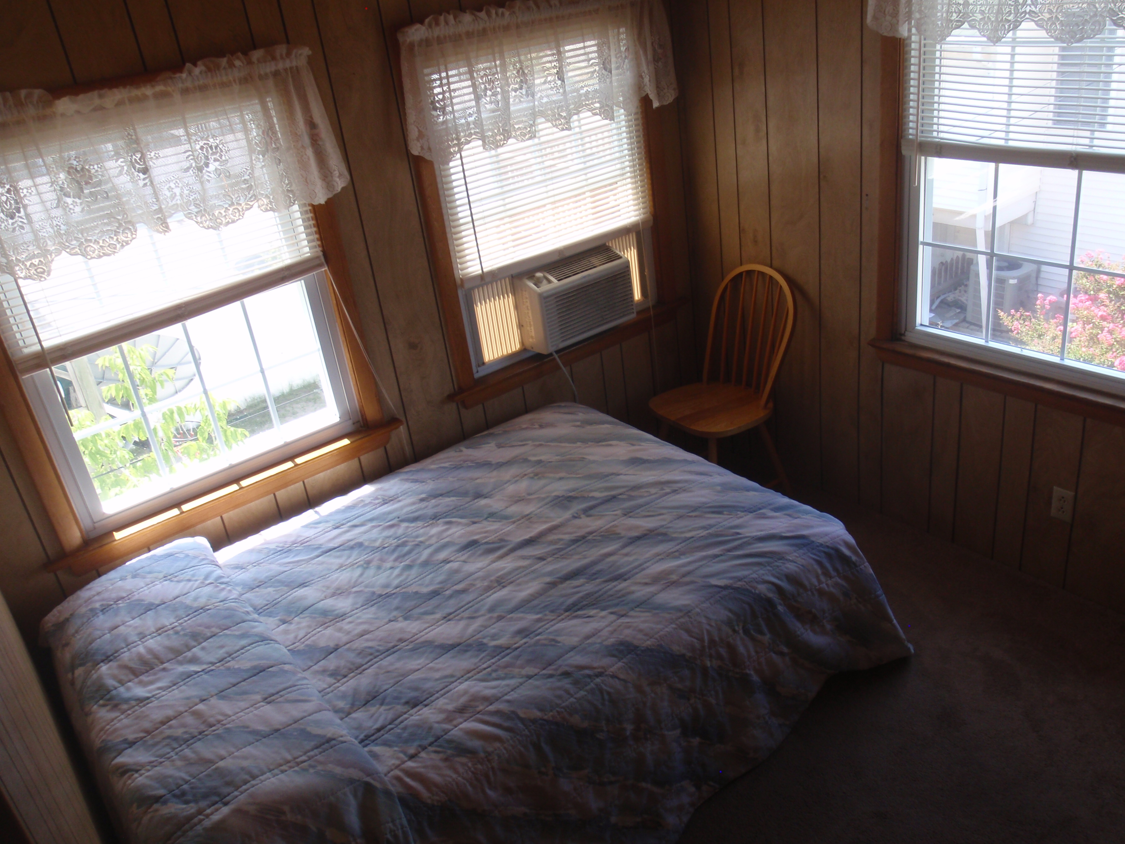 bedroom with full size bed, window a/c unit, and chair